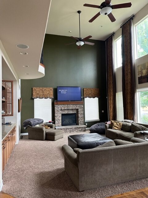 Living room with a stone fireplace and tall windows