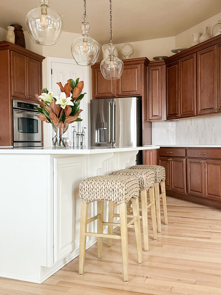 Kitchen island with woven stools and pendant lighting